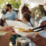 volunteers handing out meal boxes at a community thanksgiving event