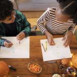 kids drawing thanksgiving pictures at a table with pumpkins