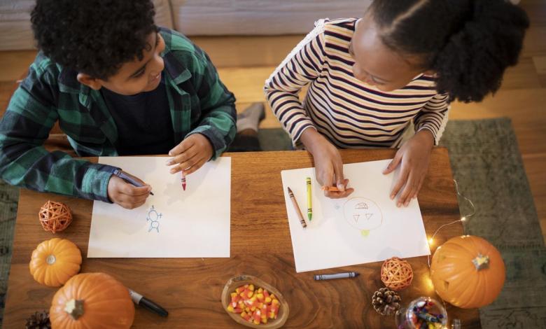 kids drawing thanksgiving pictures at a table with pumpkins