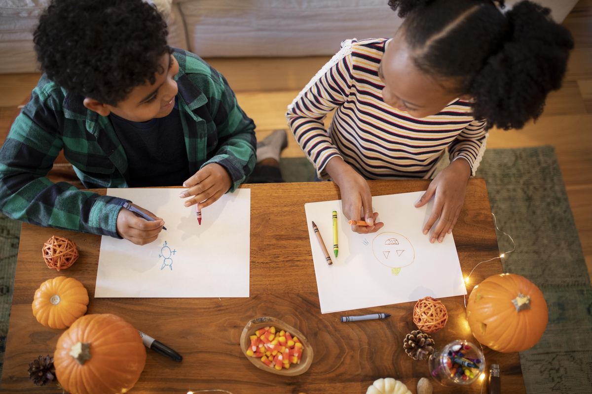 kids drawing thanksgiving pictures at a table with pumpkins